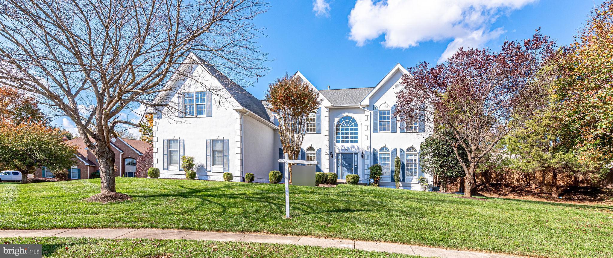 a view of a white house next to a yard with big trees