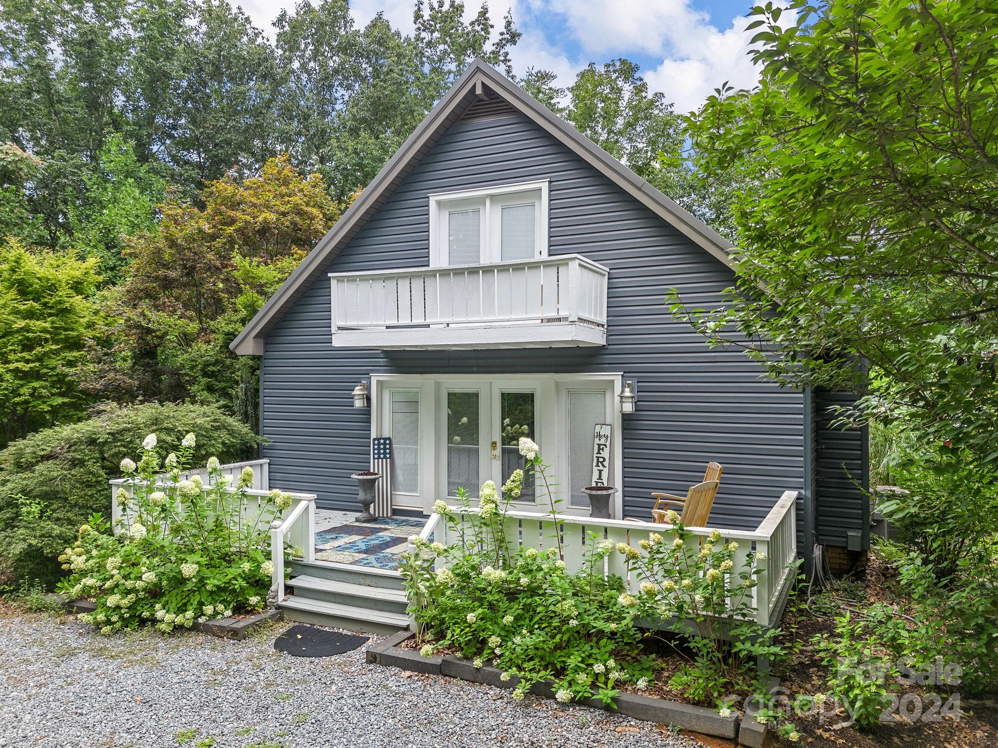 a view of a house with a yard plants and large tree