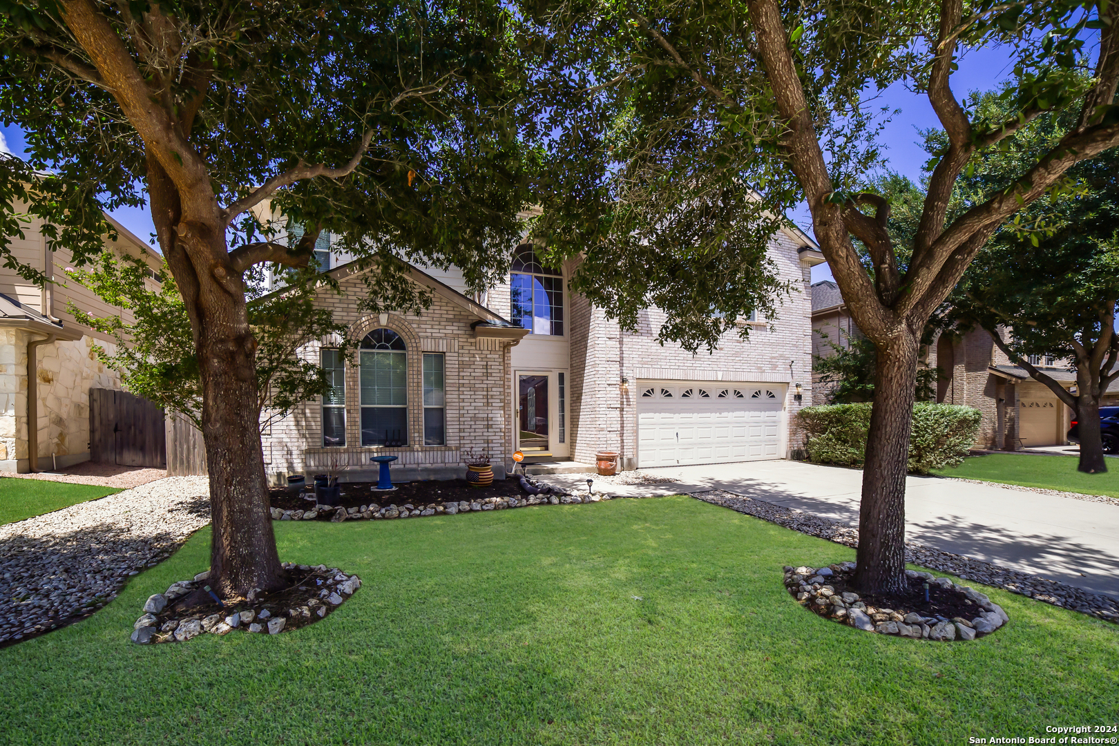 a front view of a house with a garden and tree