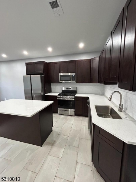 a kitchen with kitchen island granite countertop a sink counter top space and stainless steel appliances