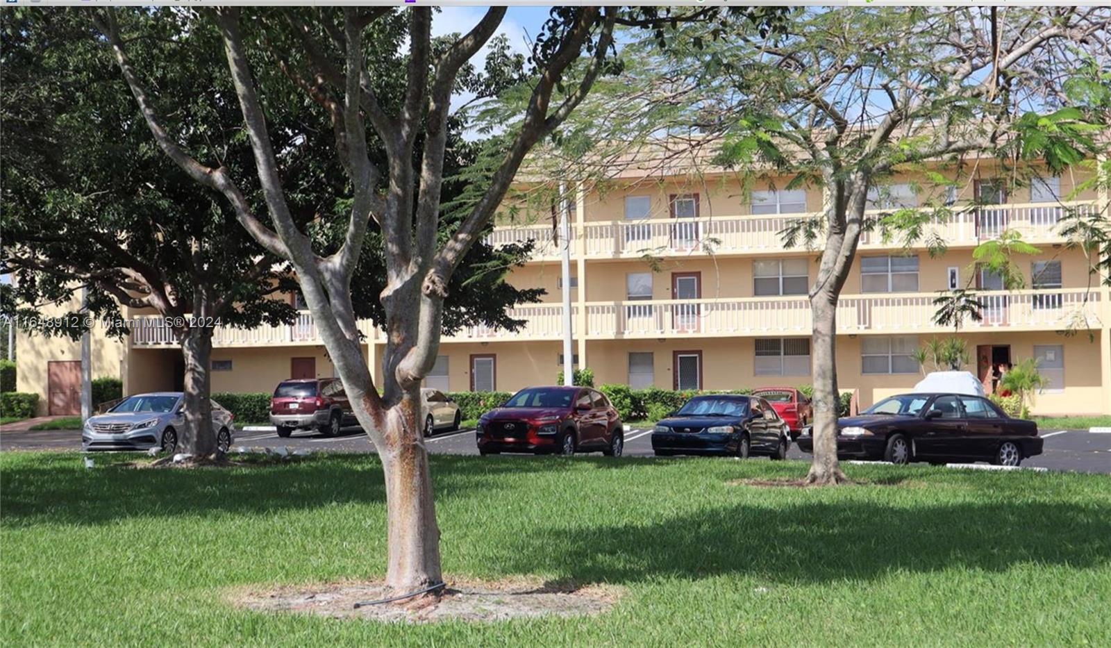 a front view of a building with garden and trees