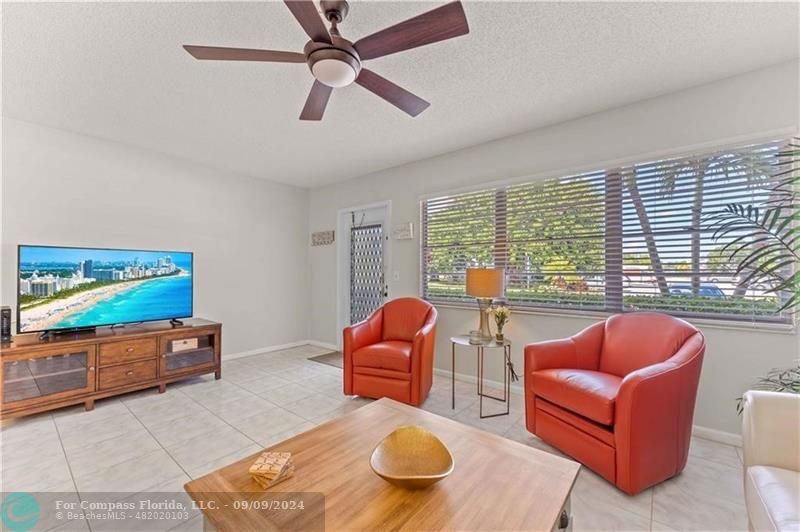 a living room with furniture ceiling fan and a floor to ceiling window