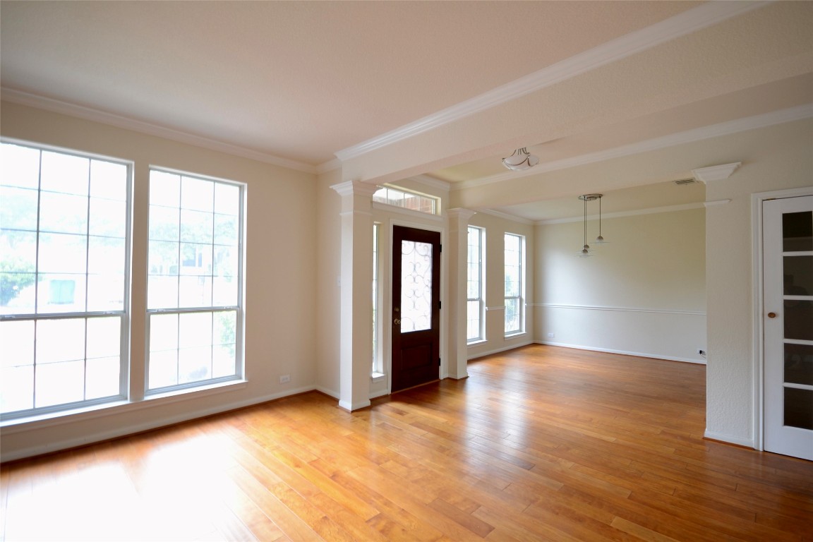 a view of an empty room with wooden floor and a window