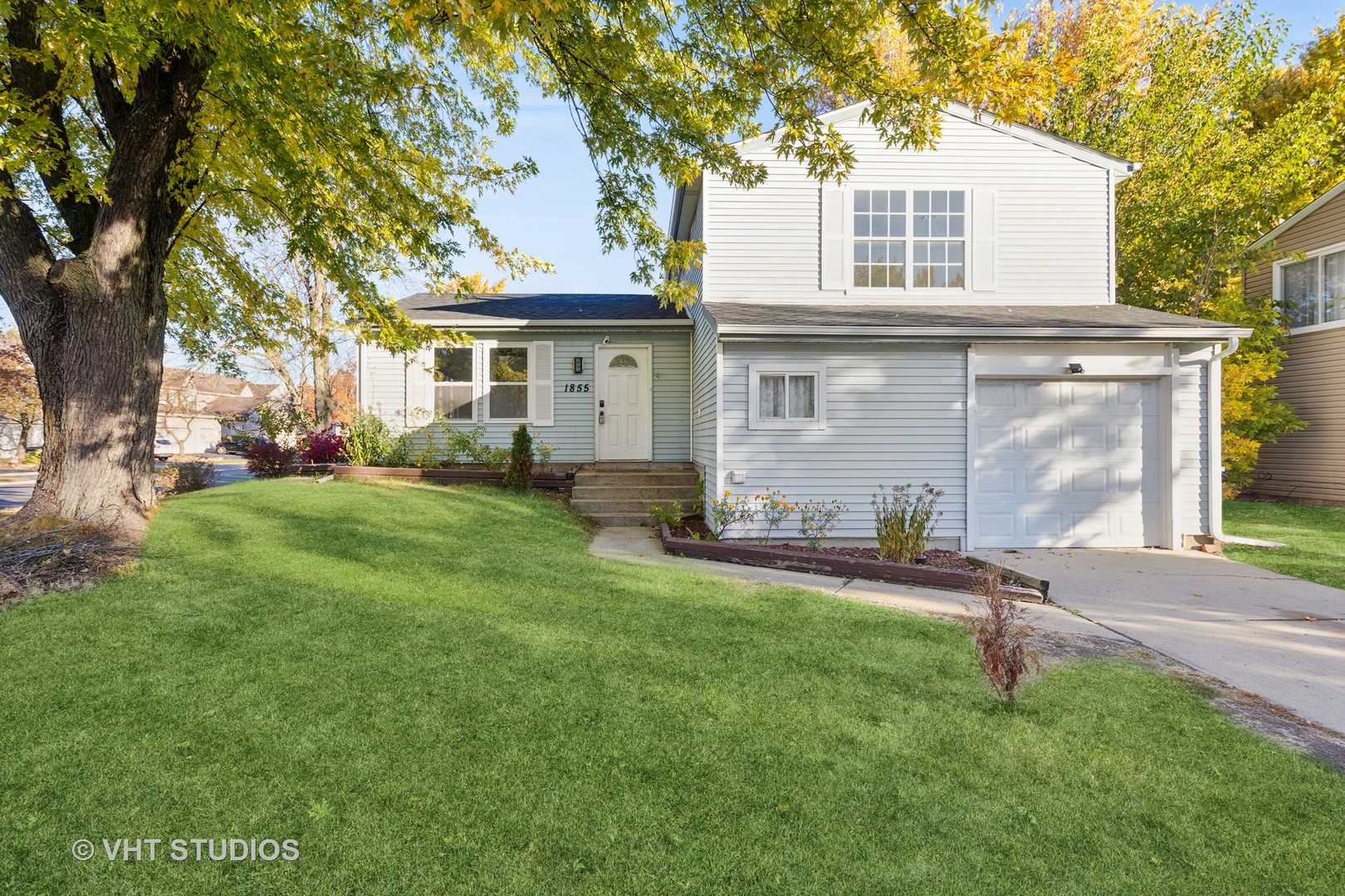 a front view of a house with a yard and trees