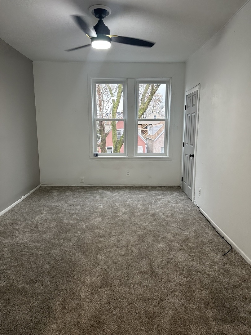 an empty room with windows and ceiling fan