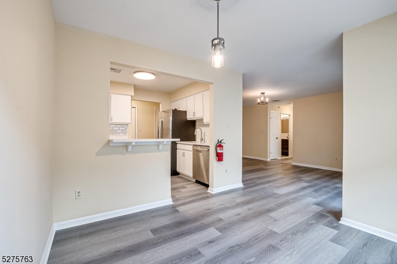 a view of a kitchen and an empty room with wooden floor