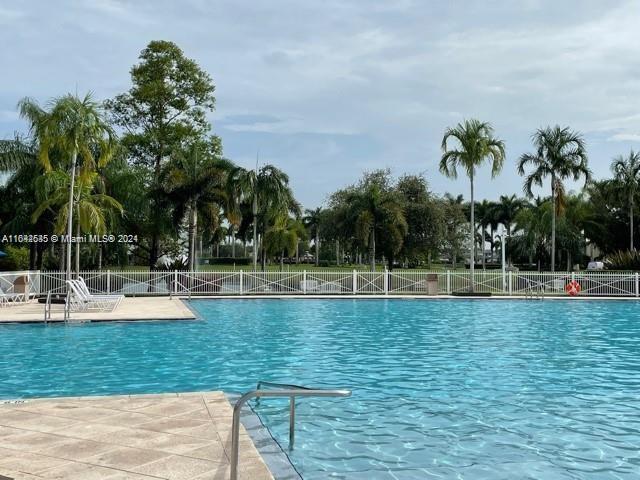 a view of a swimming pool with a lawn chairs under palm trees