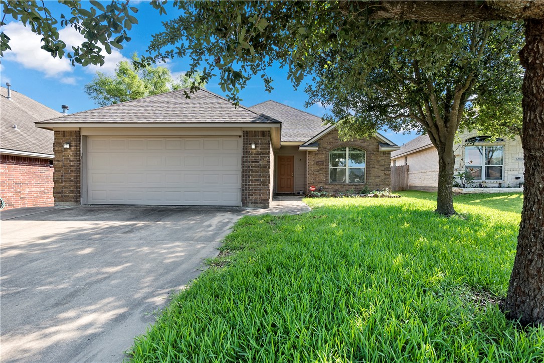 Ranch-style home featuring a front yard and a gara