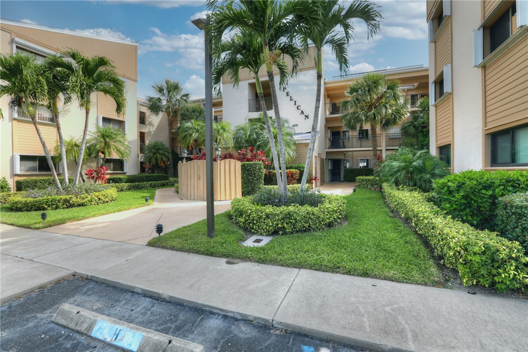 a view of a white house with a yard and palm trees