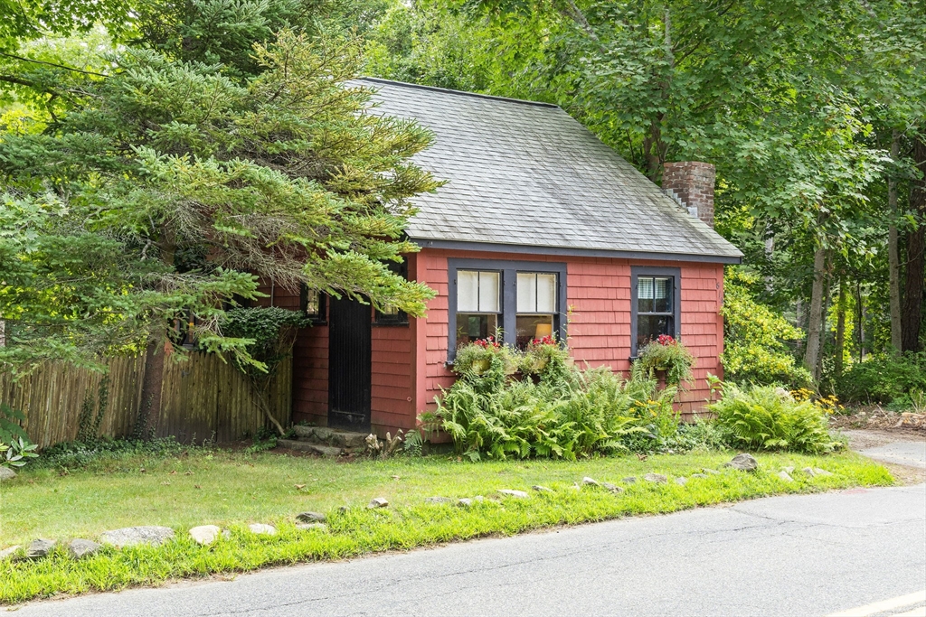 a brick house with a yard plants and big trees