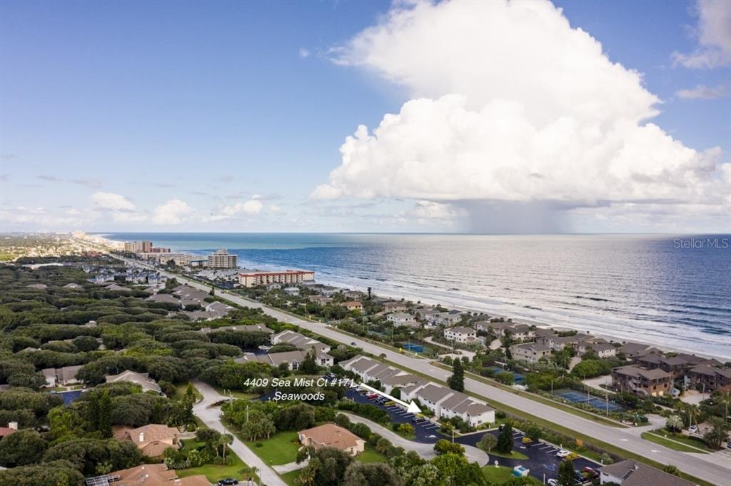 an aerial view of ocean and residential houses with outdoor space