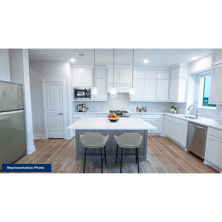 a open kitchen with stainless steel appliances granite countertop a sink a stove a refrigerator with white cabinets