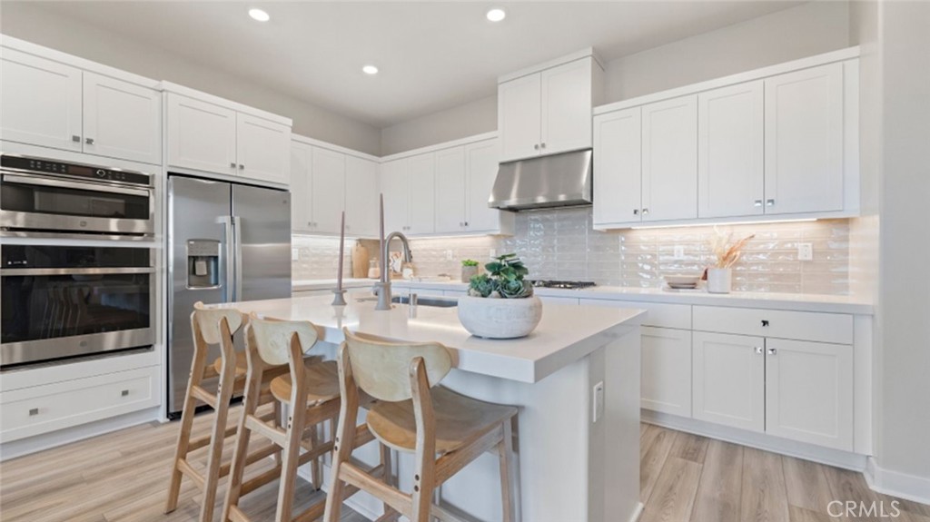 a kitchen with stainless steel appliances white cabinets and wooden floor