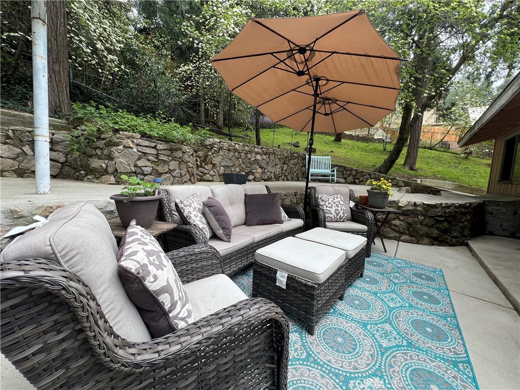 a view of a patio with couches table and chairs under an umbrella with a small yard