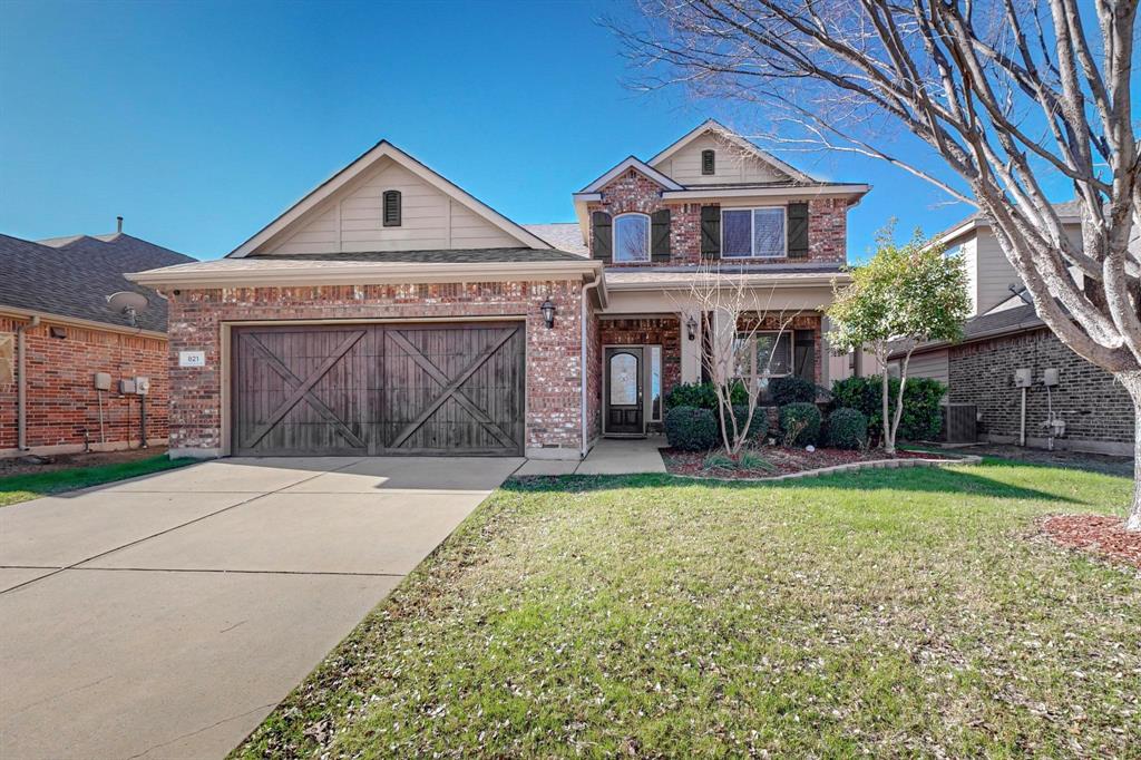 View of front facade featuring a garage and a front lawn