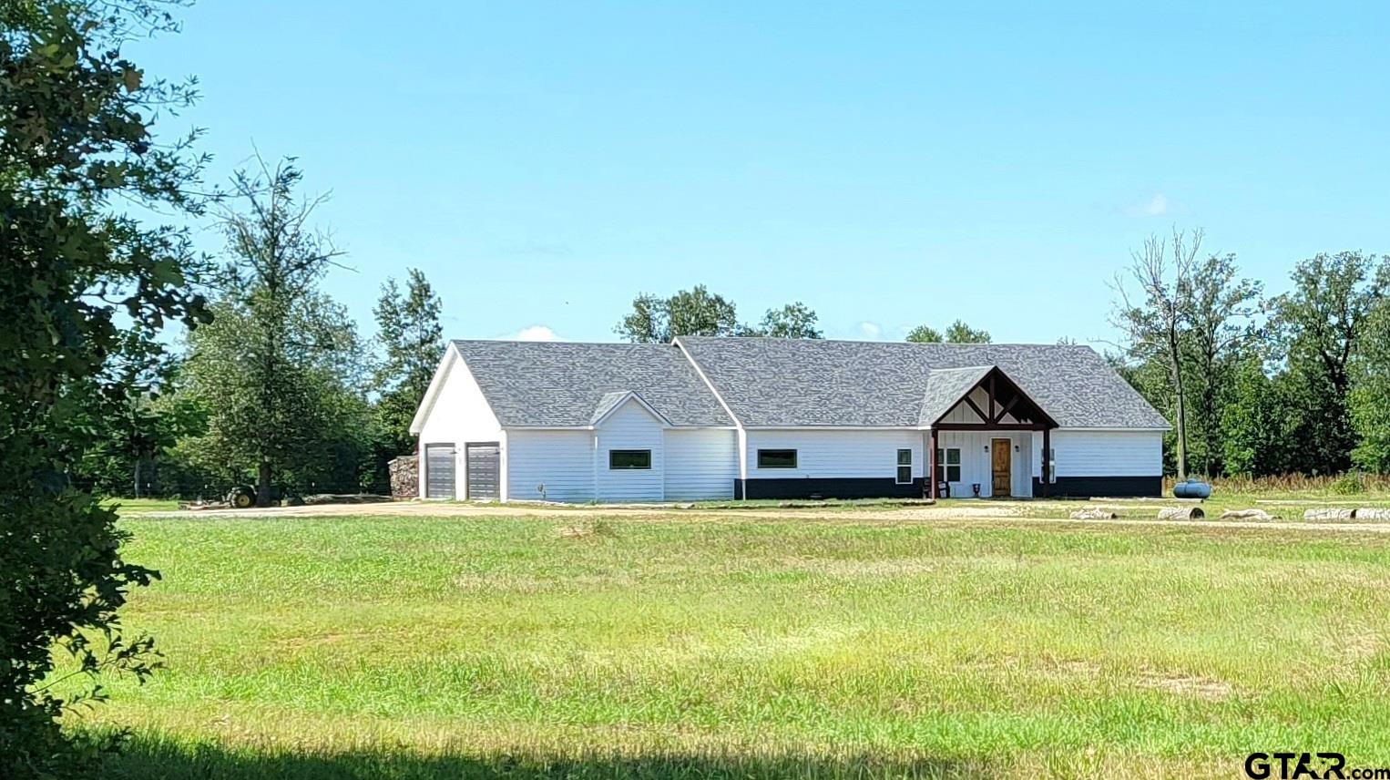 a view of house with yard and trees in the background