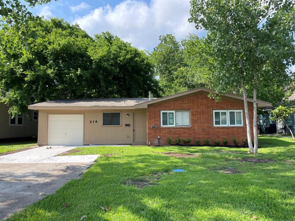 a house that is sitting in the grass with large trees and plants