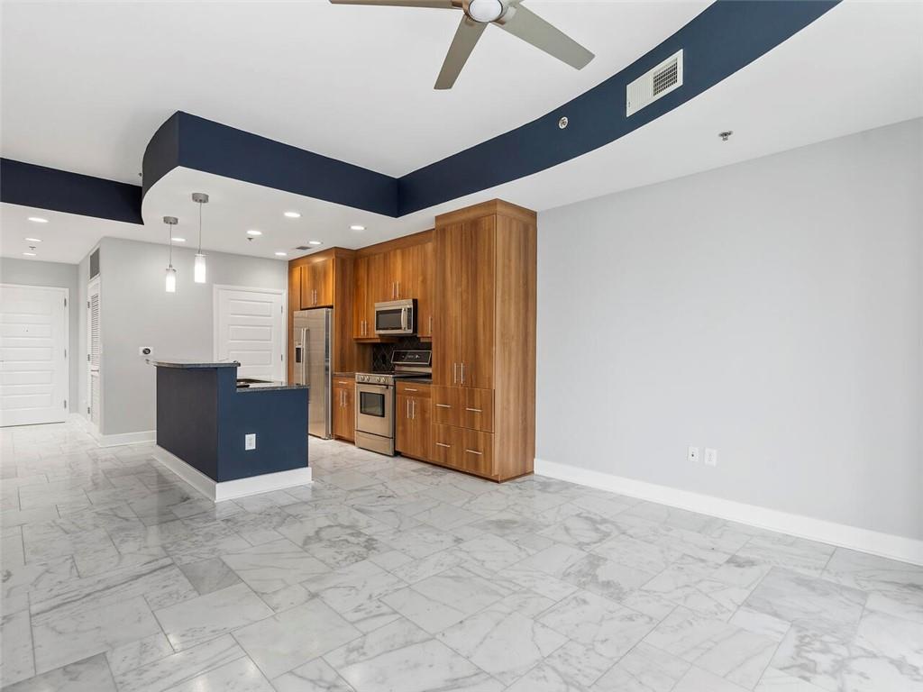 a kitchen with stainless steel appliances kitchen island granite countertop a refrigerator and a sink