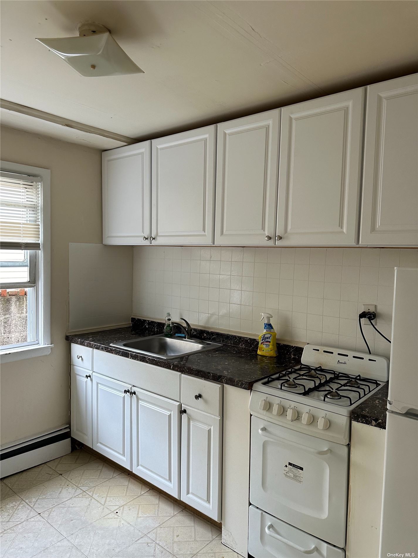 a kitchen with granite countertop a stove a sink dishwasher and white cabinets