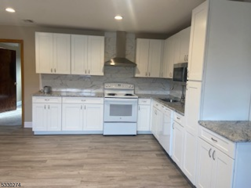 a kitchen with stainless steel appliances granite countertop a stove a sink and white cabinets