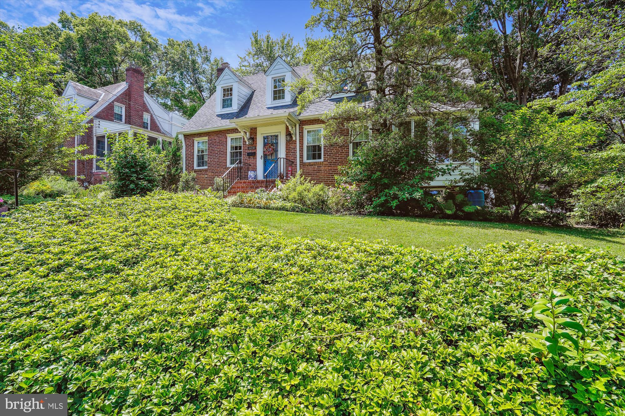 a view of a brick house with a big yard and large trees