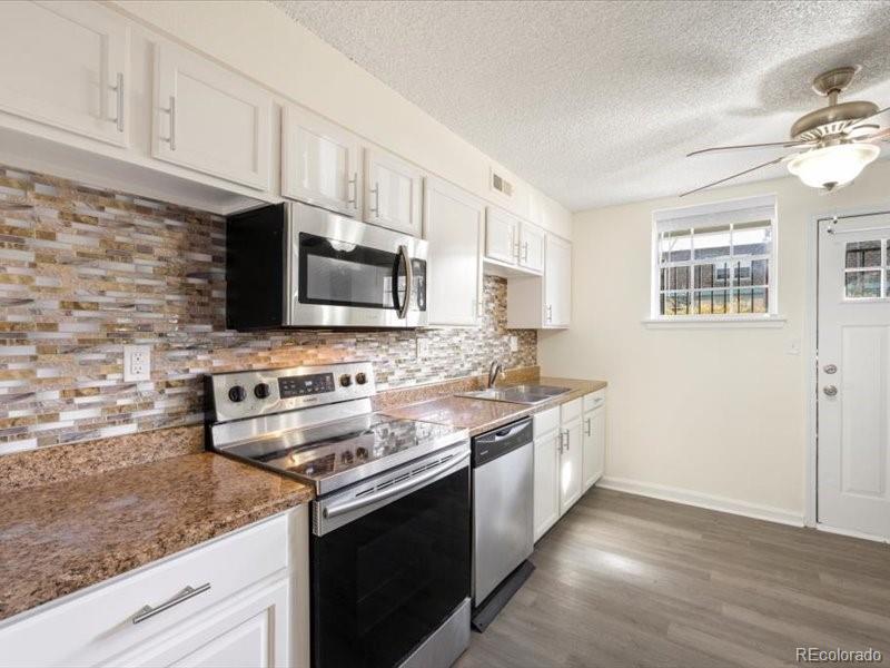 a kitchen with stainless steel appliances granite countertop a stove a sink and a microwave