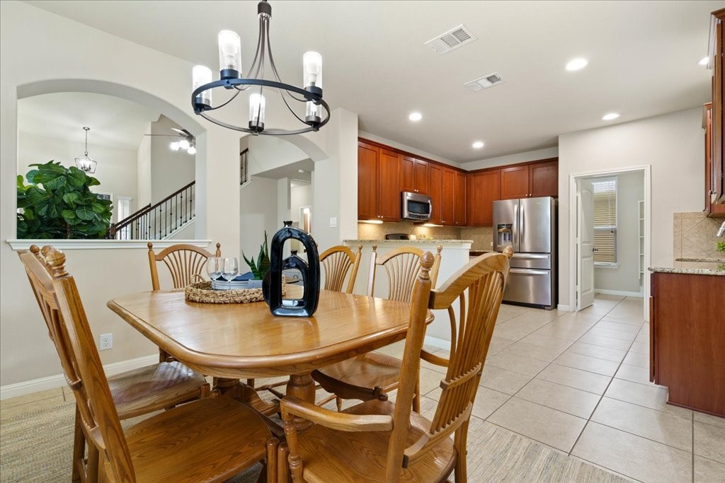 a dining room filled chandelier and kitchen view