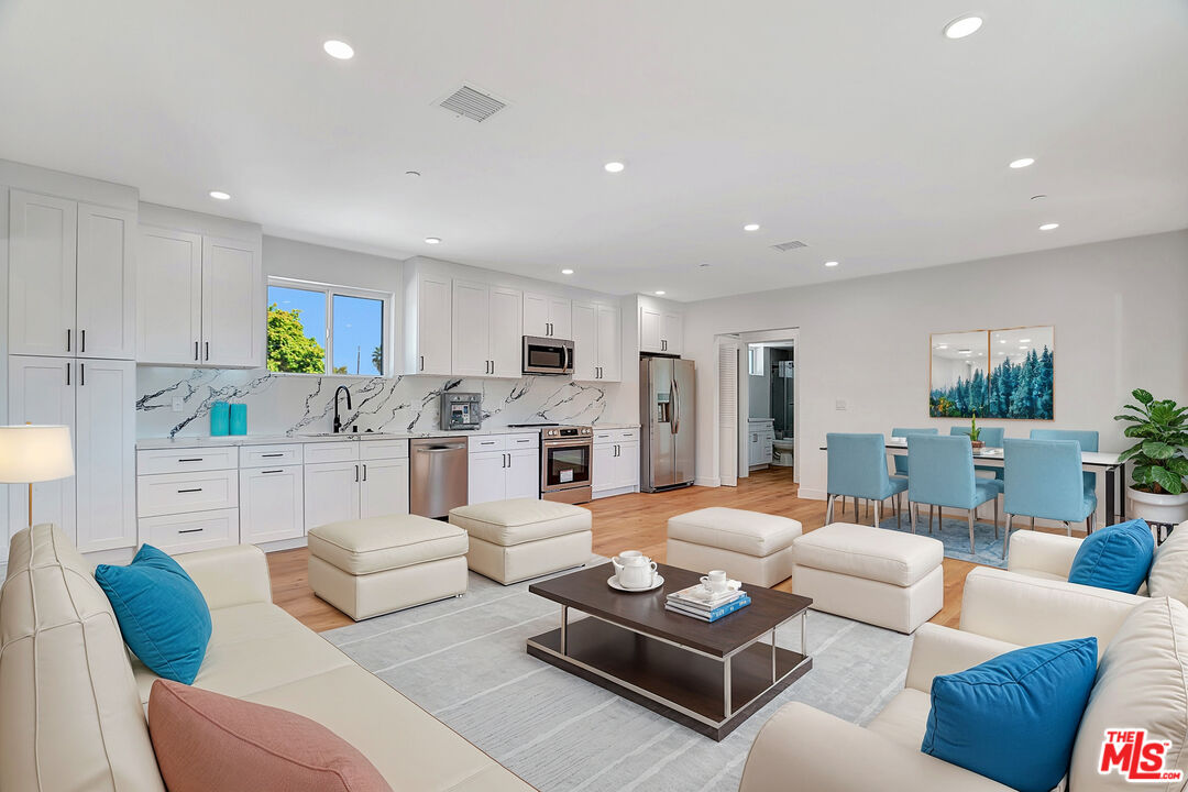 a living room with furniture kitchen view and a chandelier