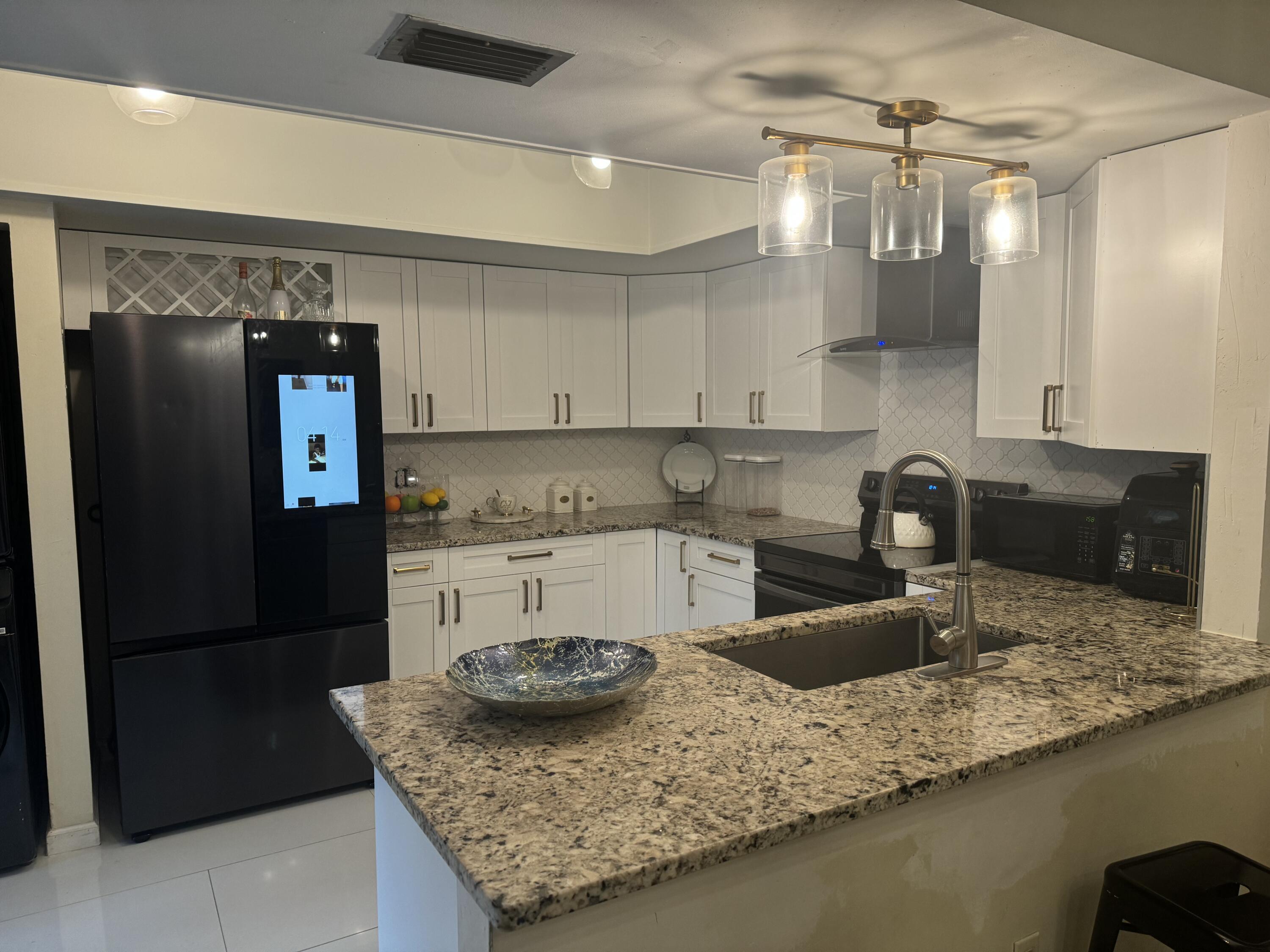 a kitchen with stainless steel appliances granite countertop a sink a refrigerator and a granite counter tops