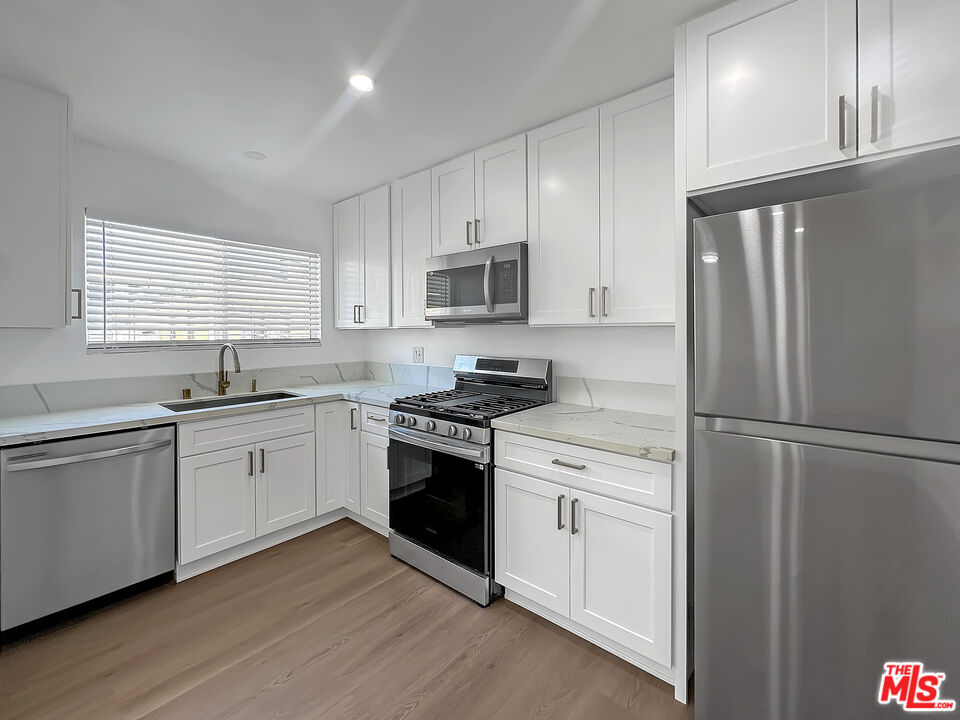 a kitchen with granite countertop white cabinets and white stainless steel appliances