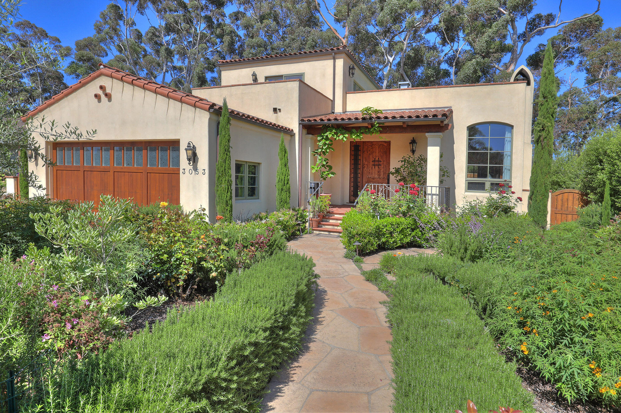 a view of a house with potted plants and a large tree