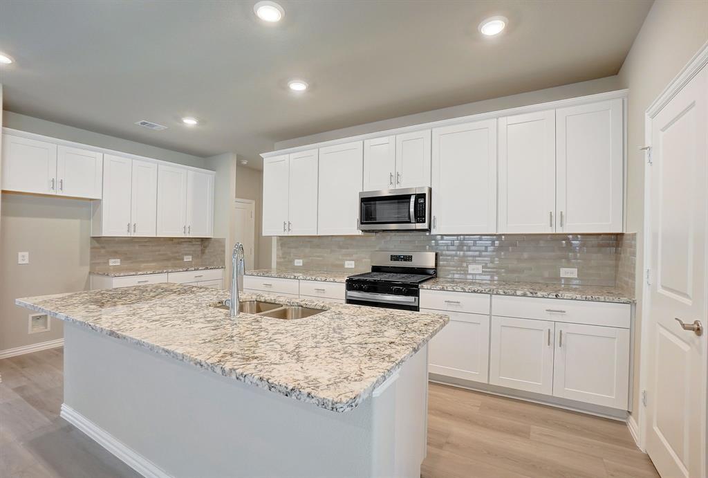 a kitchen with sink stove microwave and cabinets