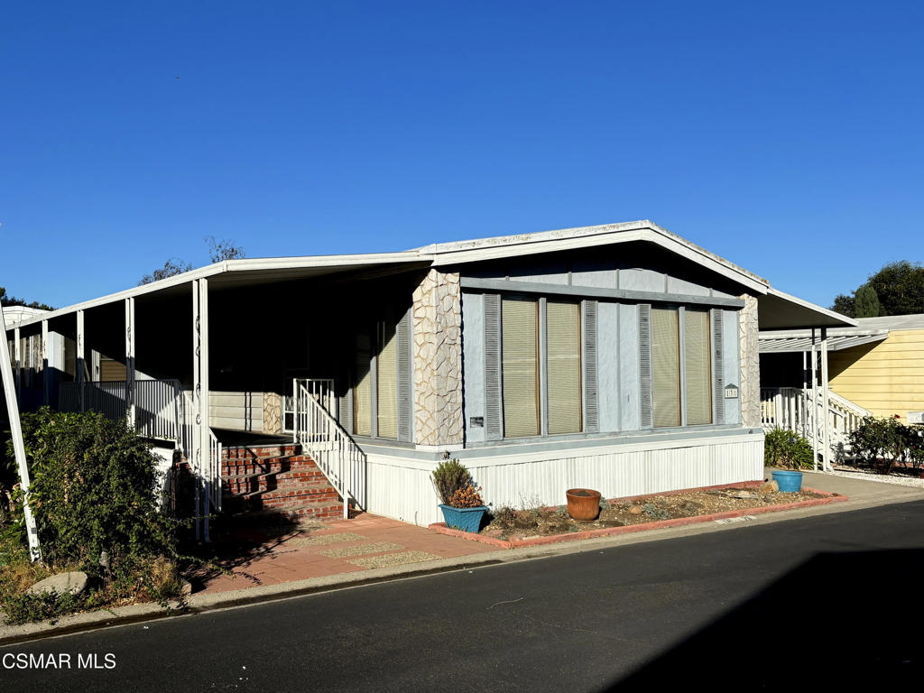 a backyard of a house with table and chairs under an umbrella