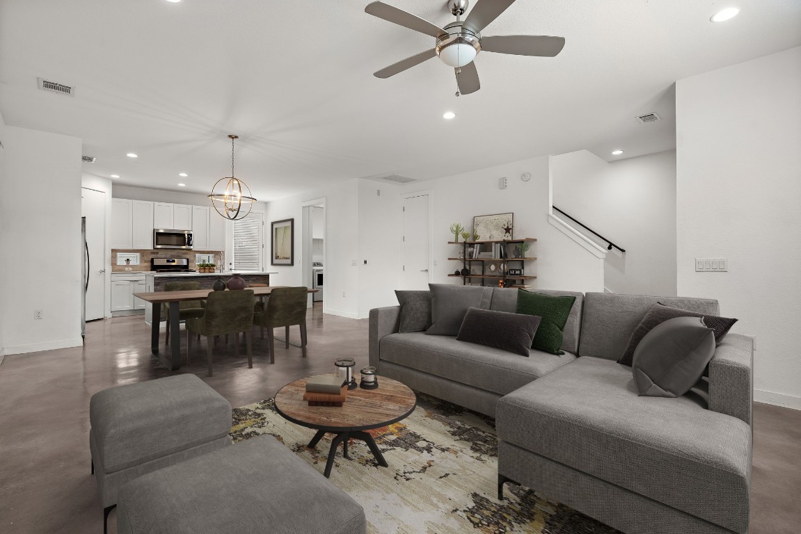 a living room with furniture kitchen view and a wooden floor