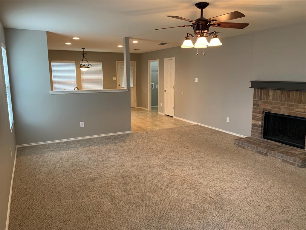 a view of an empty room with a fireplace and a chandelier fan