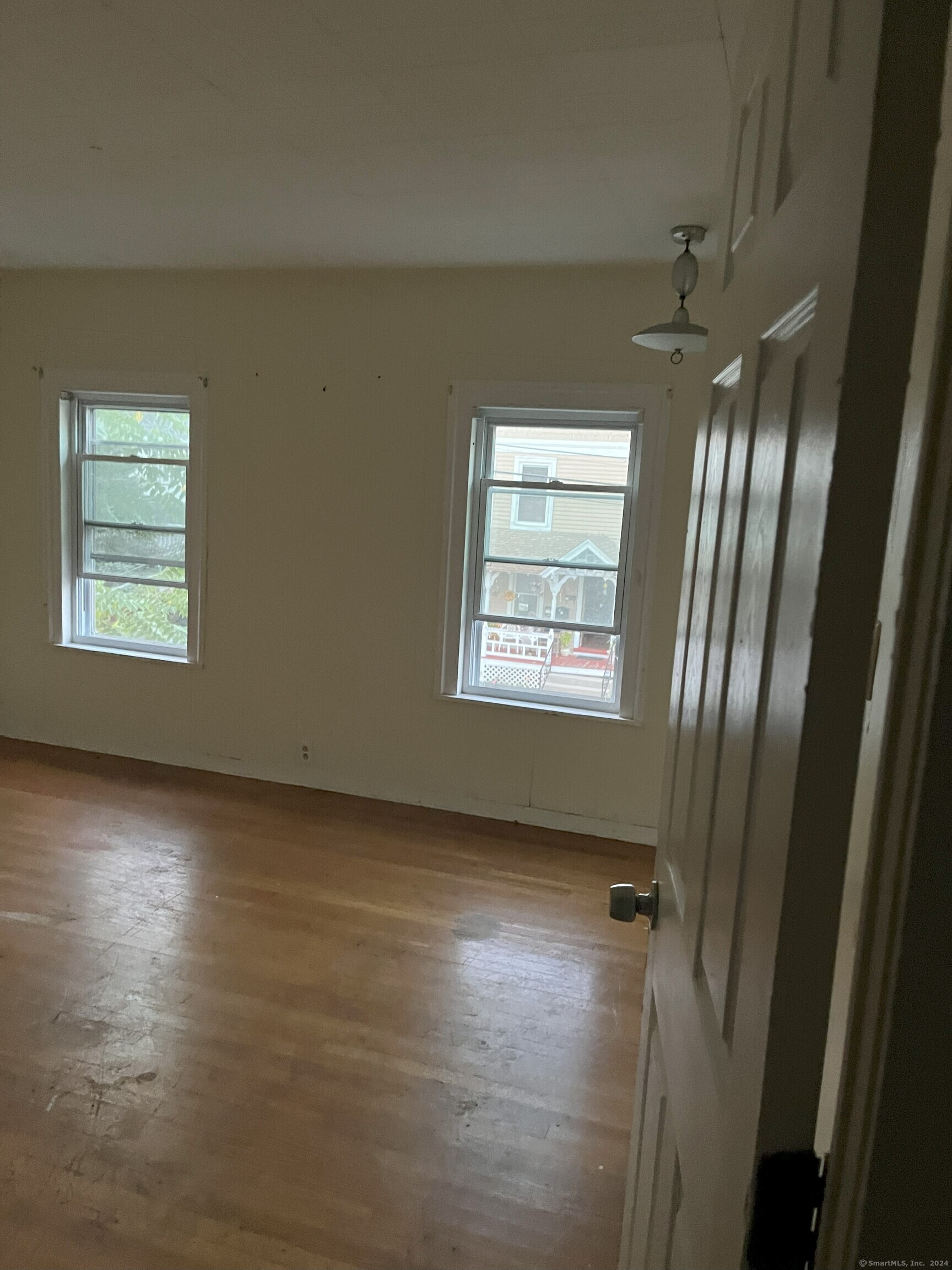 an empty room with wooden floor and windows