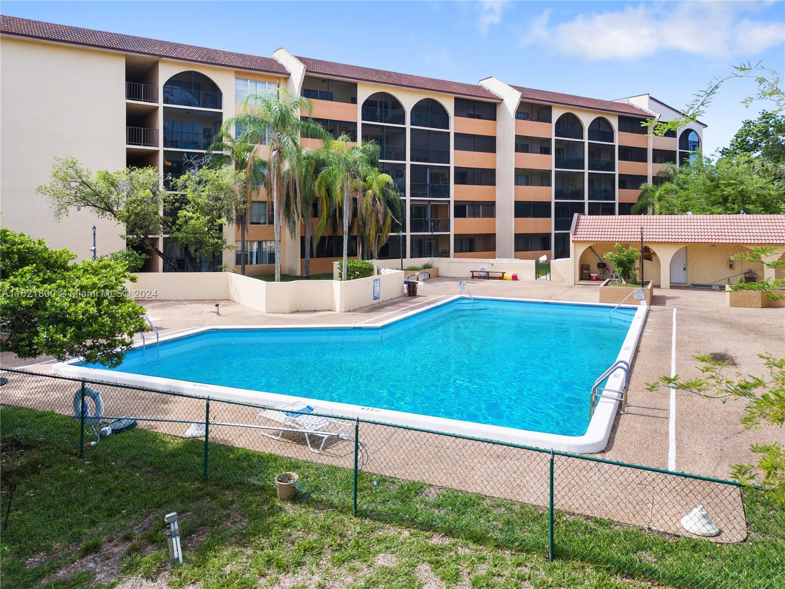 a view of pool with lawn chairs and large trees