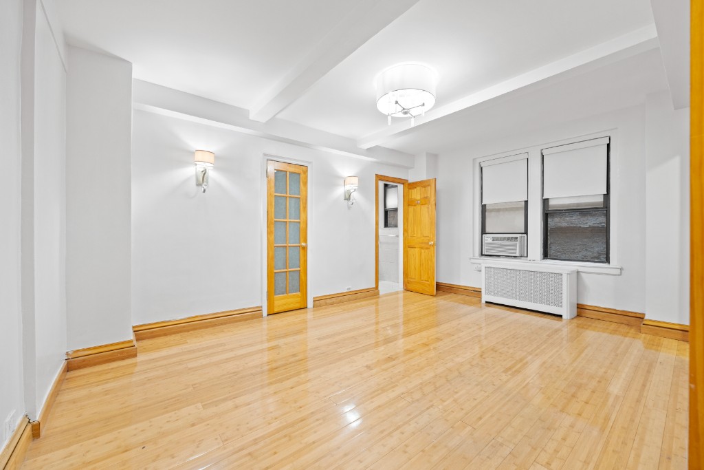 a view of an empty room with window and wooden floor