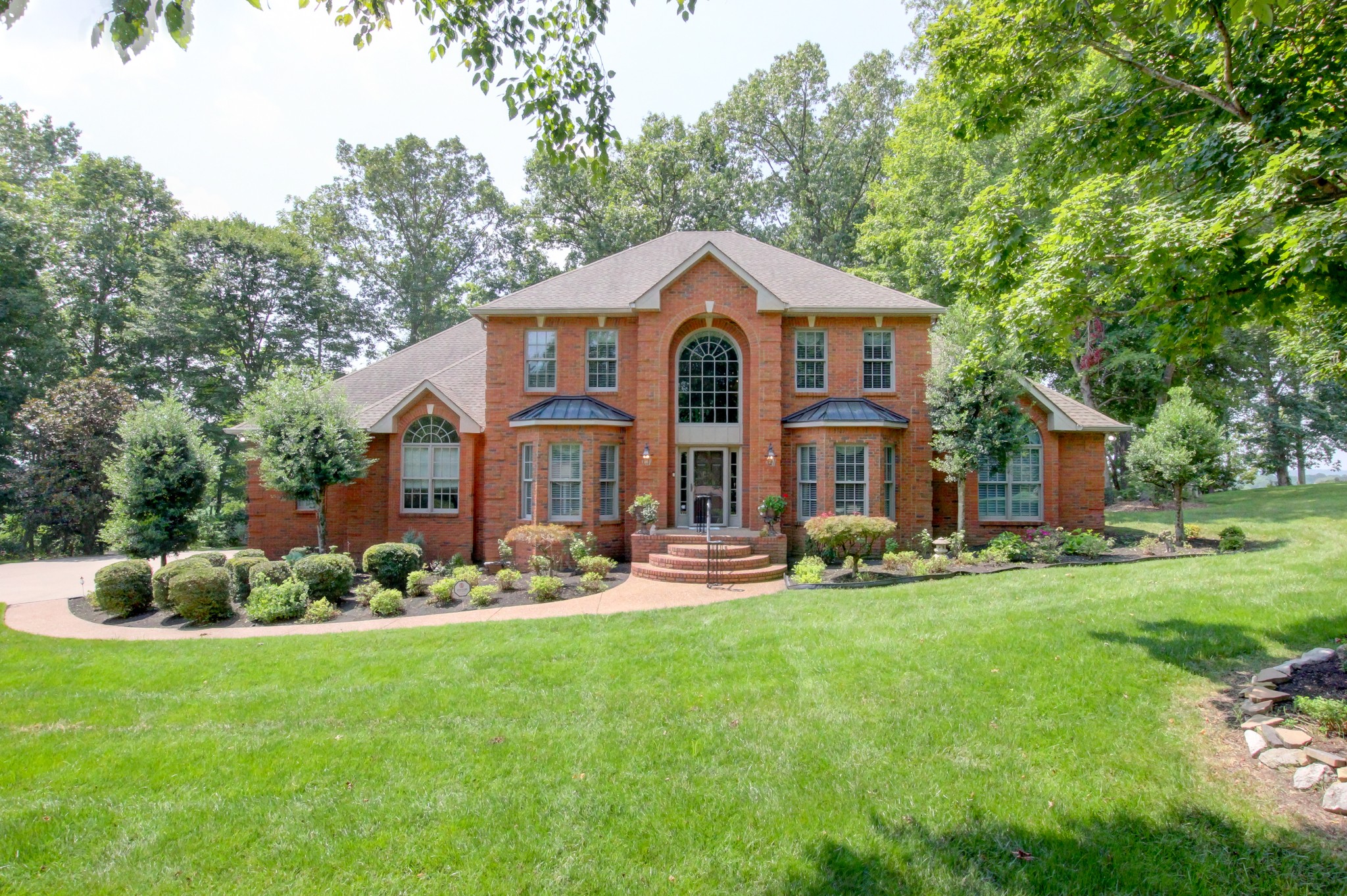 a front view of a house with a garden and trees