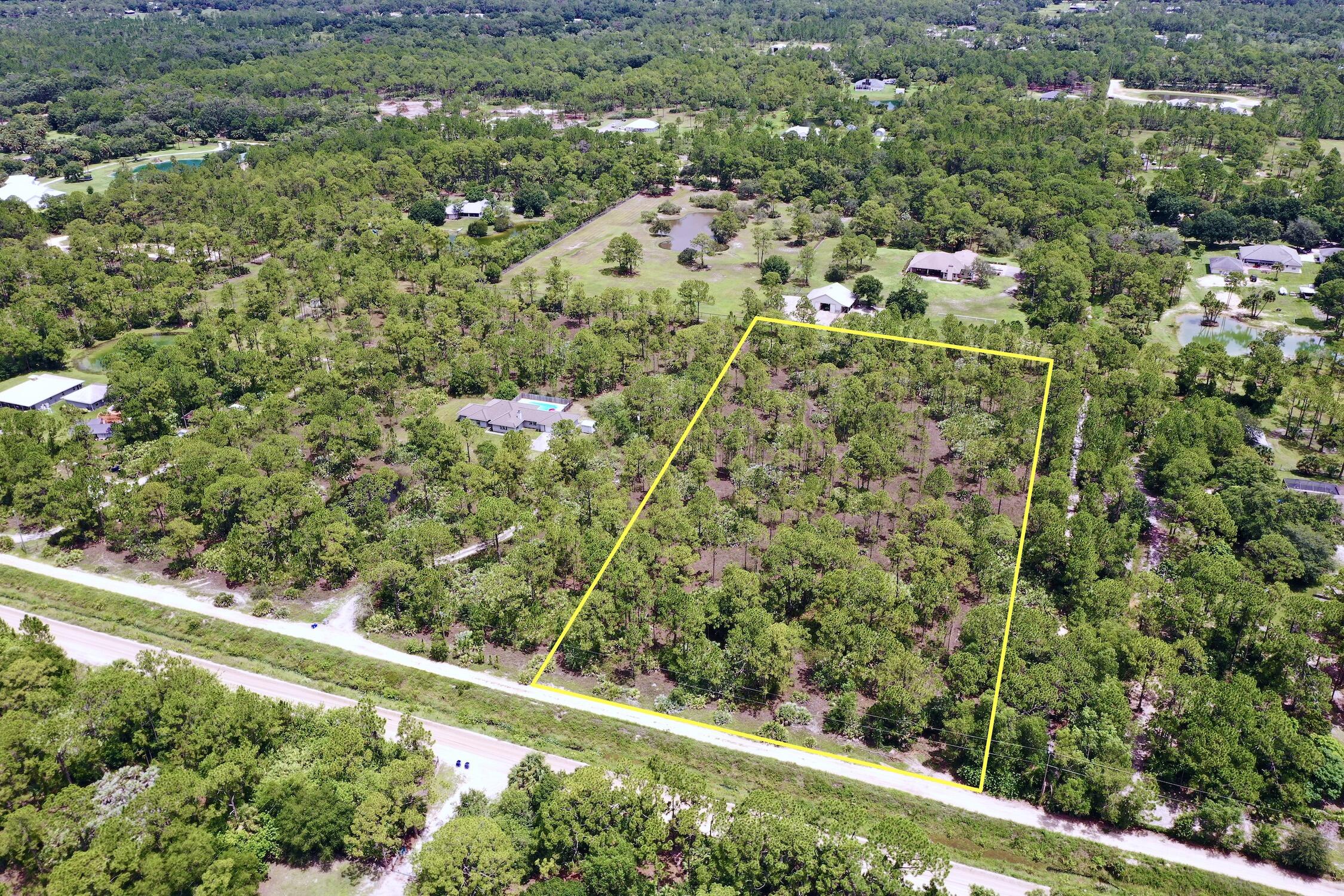 an aerial view of residential houses with outdoor space and trees