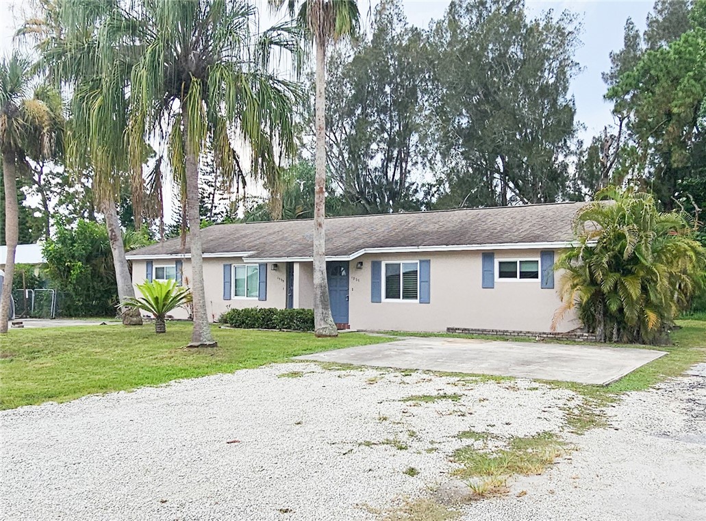 a view of a yard in front of a house with a large tree