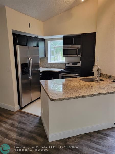 a kitchen with granite countertop a refrigerator and a sink