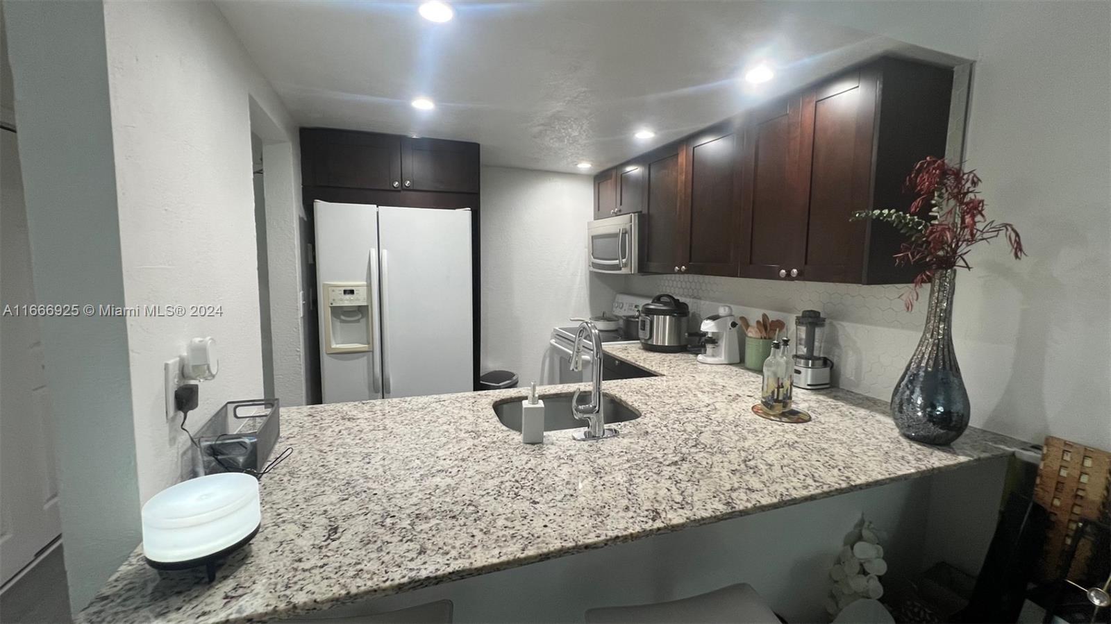 a bathroom with a granite countertop sink a toilet and a mirror