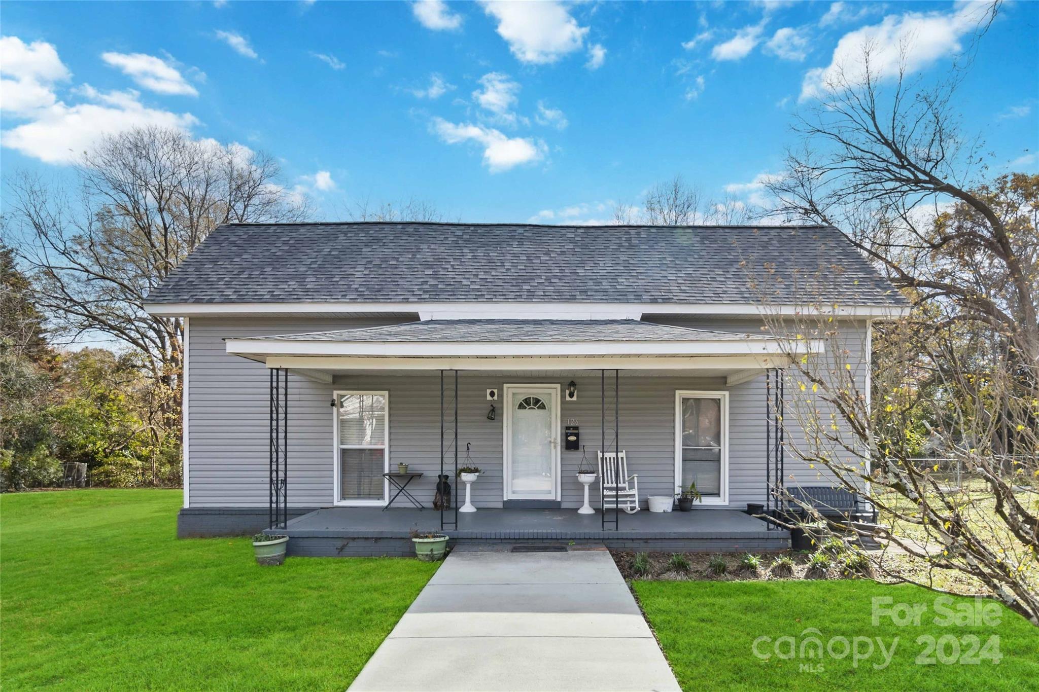 a front view of a house with a yard and potted plants