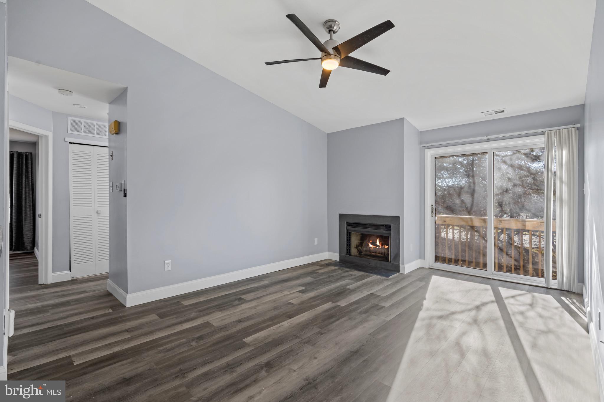 a view of a livingroom with a fireplace a ceiling fan and window