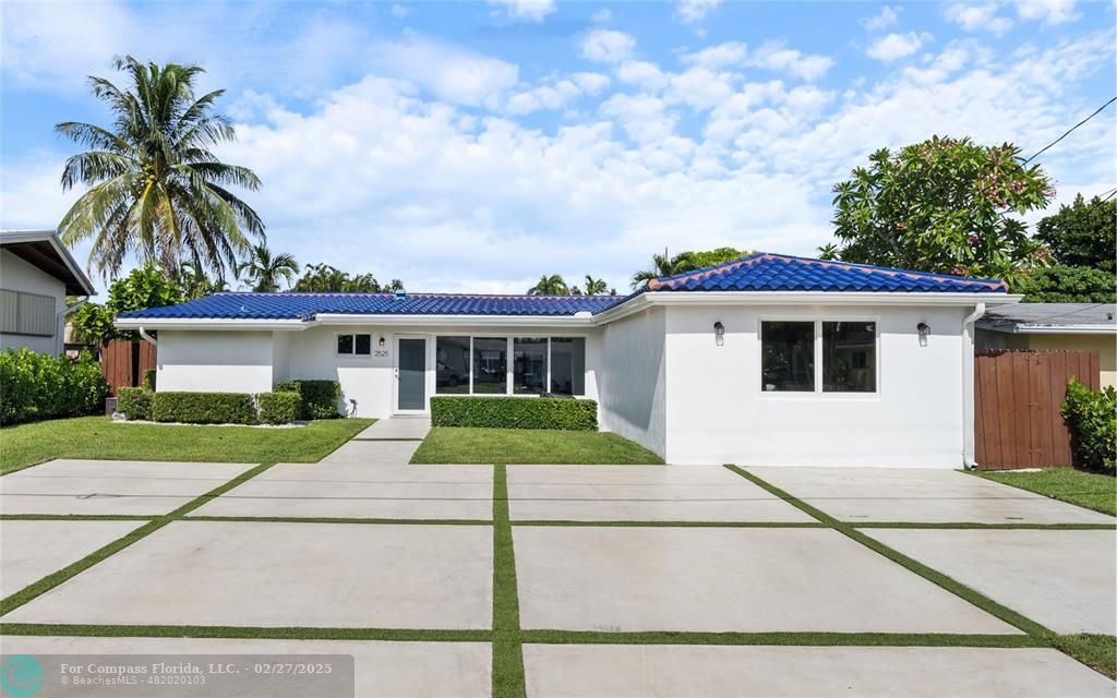 a view of a white house next to a yard with plants and trees