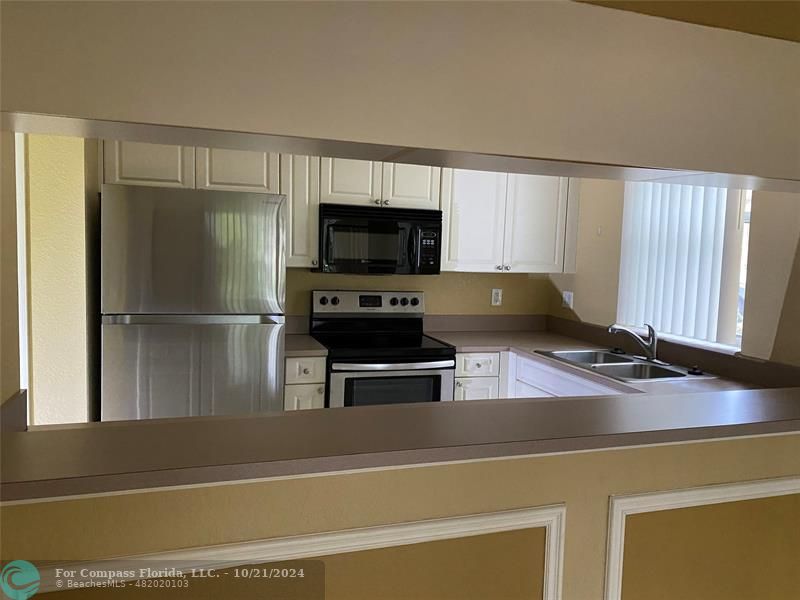 a kitchen with granite countertop a refrigerator and a stove top oven