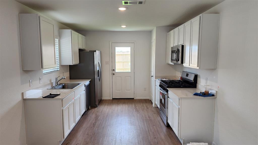 a kitchen with granite countertop a sink stove and refrigerator