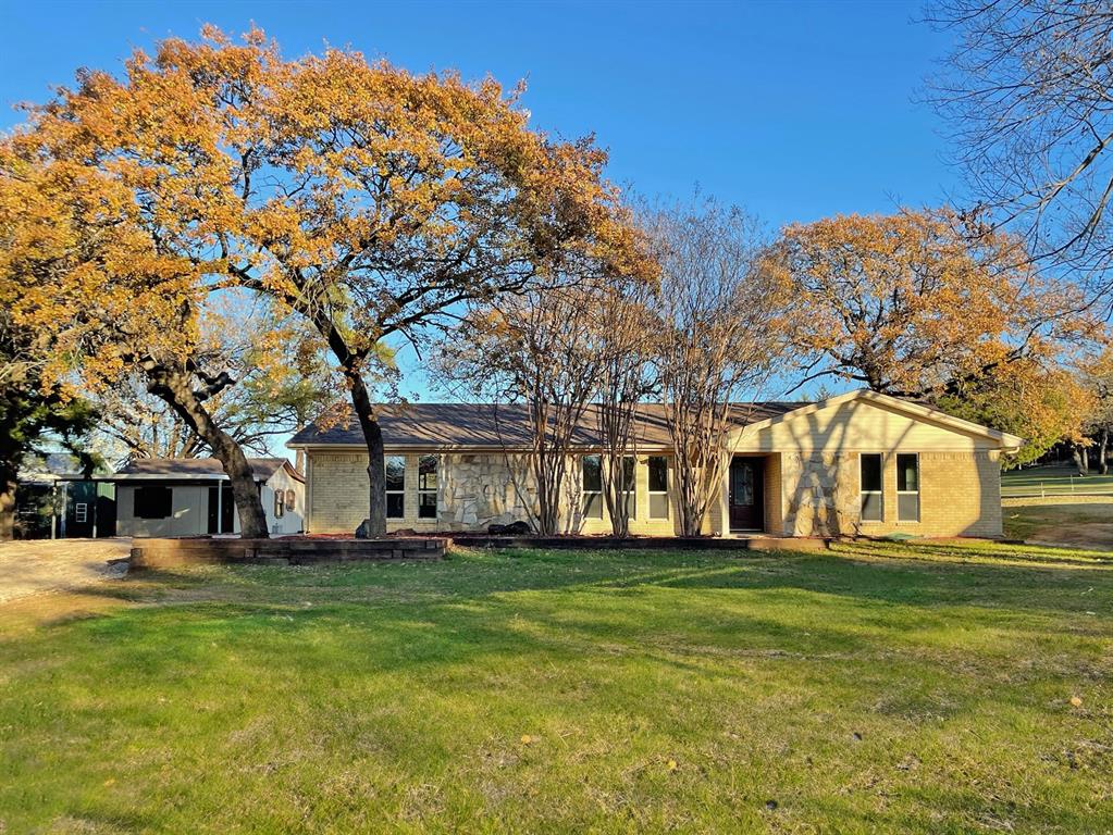 a view of a white house with a big yard and large trees