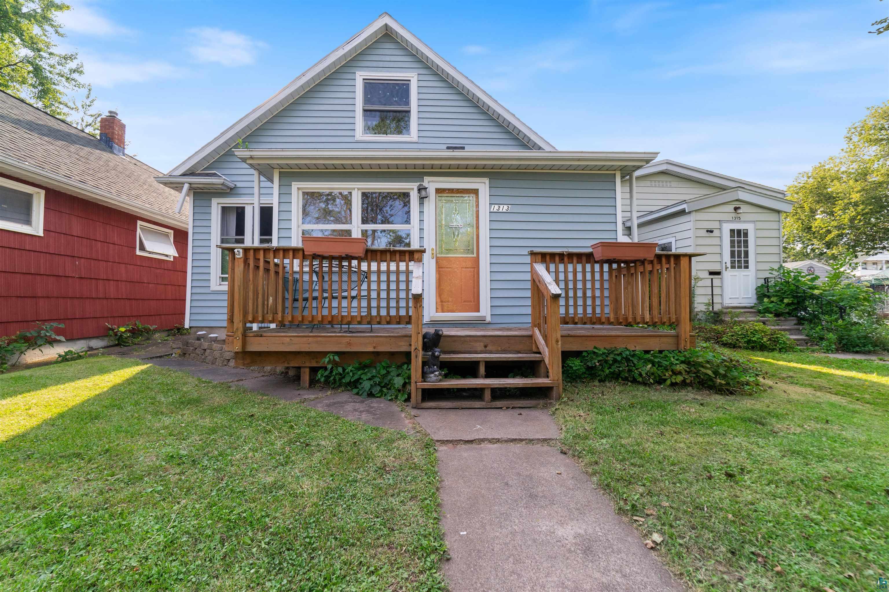 Rear view of house featuring a lawn and a wooden deck